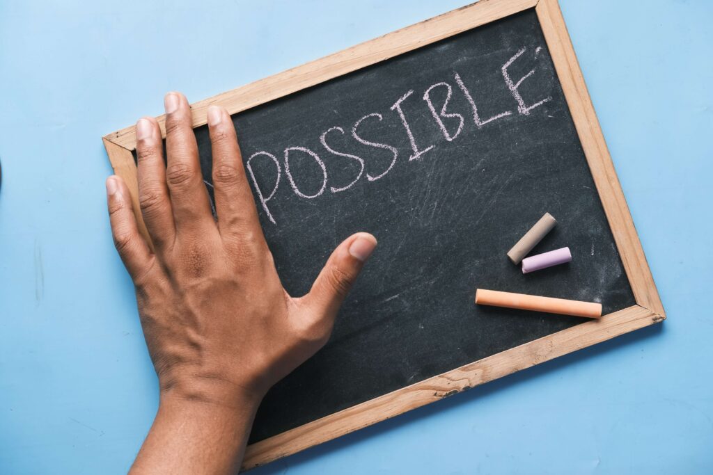 A chalkboard with the word POSSIBLE. A hand seems to cover the letters IM that appear before POSSIBLE.