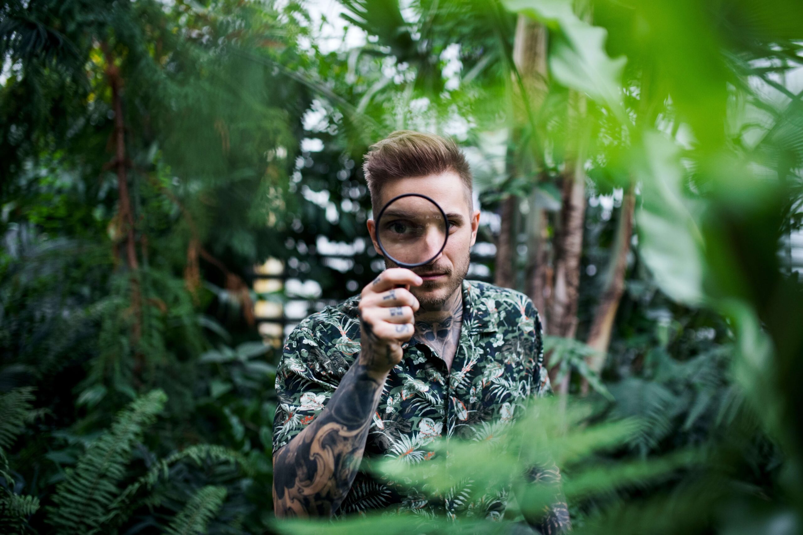 Person with a magnifying glass surrounded by plants