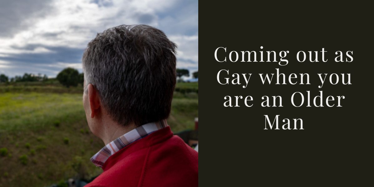 A man with grey short hair looks towards a green field with grass and trees with his back to the camera. We see him from the top of the shoulders up. The collar of a checked shirt appear from a red jumper. The caption reads "Coming out as Gay when you are an Older Man"